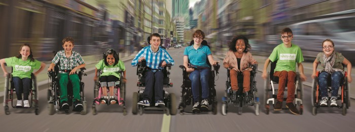 A group of children in wheelchairs lined up smiling.